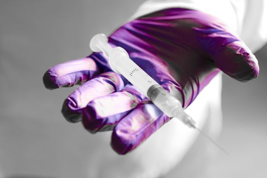 Male hand in surgical glove holding a syringe