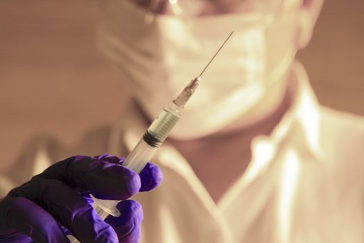 Laboratory assistant wearing protective glasses and surgery gloves holding a syringe with Covid-19 virus vaccine