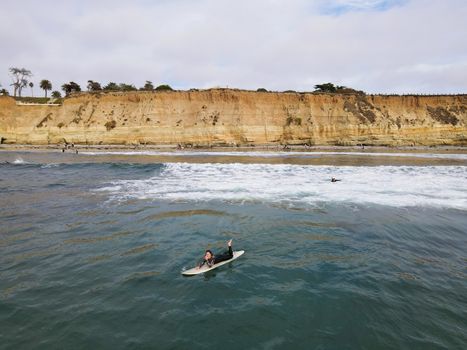 Surfers with wet suit paddling and enjoying the big waves. San Diego, California, USA. November 20th, 2020