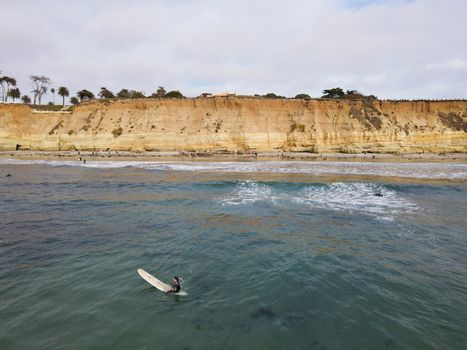 Surfers with wet suit paddling and enjoying the big waves. San Diego, California, USA. November 20th, 2020