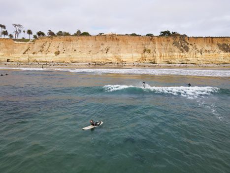 Surfers with wet suit paddling and enjoying the big waves. San Diego, California, USA. November 20th, 2020