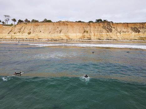 Surfers with wet suit paddling and enjoying the big waves. San Diego, California, USA. November 20th, 2020