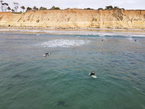 Surfers with wet suit paddling and enjoying the big waves. San Diego, California, USA. November 20th, 2020