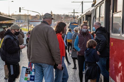 11-23-2020. Prague, Czech Republic. People walking and talking outside during coronavirus (COVID-19) at Hradcanska metro stop in Prague 6. People getting inside tram.