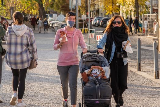 11-23-2020. Prague, Czech Republic. People walking and talking outside during coronavirus (COVID-19) at Hradcanska metro stop in Prague 6. Woman with mask walking with prem..