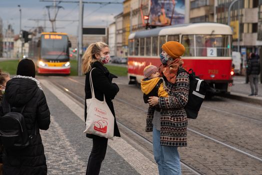 11-23-2020. Prague, Czech Republic. People walking and talking outside during coronavirus (COVID-19) at Hradcanska metro stop in Prague 6. Mother and child waiting tram