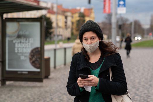 11-23-2020. Prague, Czech Republic. People walking and talking outside during coronavirus (COVID-19) at Hradcanska metro stop in Prague 6. Woman with mask waiting for tram..