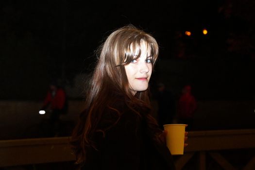 night portrait of a girl with a glass of coffee in her hand.