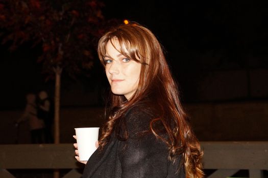 night portrait of a girl with a glass of coffee in her hand.