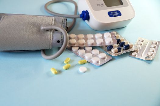 tonometer and pills on blue background, view from above, copy space