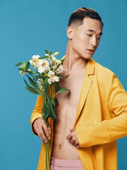 A half-naked man in a yellow jacket with a bouquet of flowers on a blue background. High quality photo