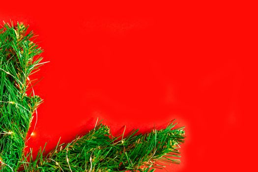 green pine branches with light bulbs on a red background frame the corner of the Christmas background, holiday lights