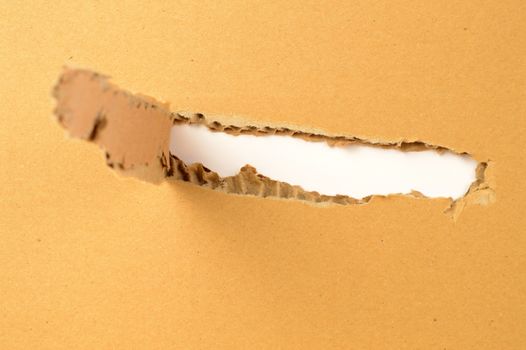 Closeup view of a damaged cardboard box with a tear through it.