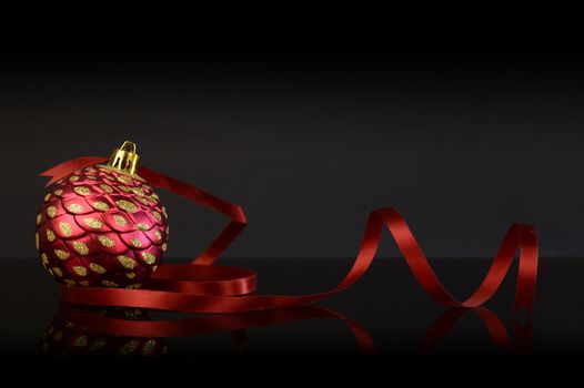 A festive red Christmas bauble with some ribbon for the holiday season.