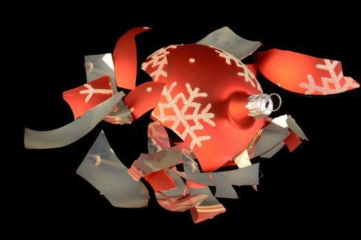 An overhead view of a broken Christmas bauble that has fallen to the floor and shattered into pieces.