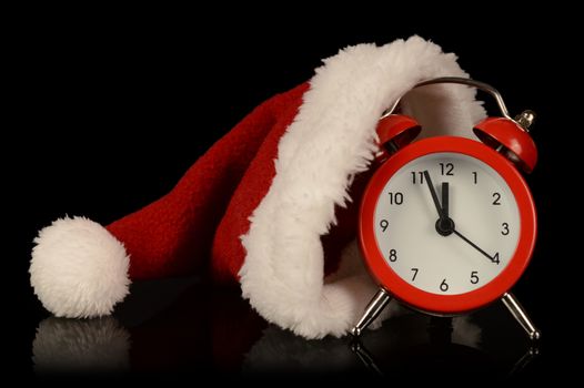 Time for Santa concept with his hat resting on a red clock almost striking midnight.