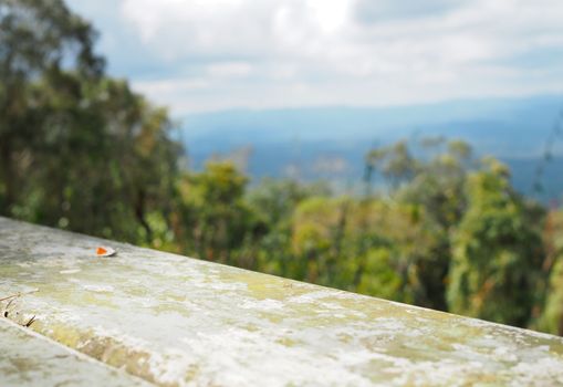 The iron table is empty on the background of forest, mountain and sky.