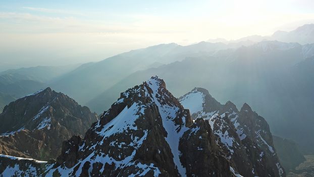 Huge snow mountains. View from the top of the drone. In places, you can see small people climbing to the top. Panorama of steep peaks and rocks, snow cornices. Mountaineering class. Extreme rest.