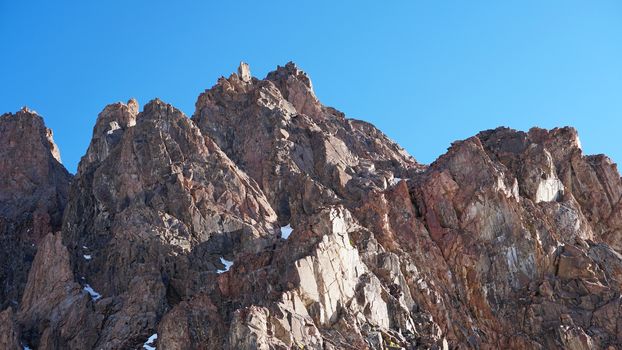 Huge snow mountains. View from the top of the drone. In places, you can see small people climbing to the top. Panorama of steep peaks and rocks, snow cornices. Mountaineering class. Extreme rest.