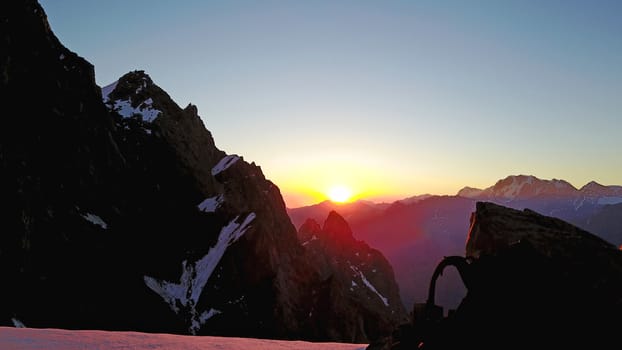 Epic red dawn on top of snowy mountains. Top view from a drone. Huge rocks covered with snow, the ledge of snow overhangs. An avalanche-prone place. Climb to the peak. Flying above the peak. Almaty