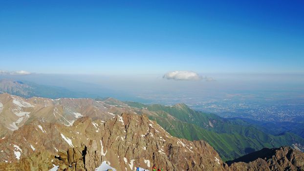 Huge snow mountains. View from the top of the drone. In places, you can see small people climbing to the top. Panorama of steep peaks and rocks, snow cornices. Mountaineering class. Extreme rest.