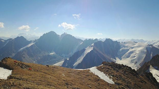 Huge snow mountains. View from the top of the drone. In places, you can see small people climbing to the top. Panorama of steep peaks and rocks, snow cornices. Mountaineering class. Extreme rest.