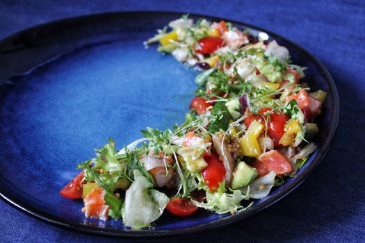 Vegetable salad of cherry tomatoes onions and herbs on a blue background.Texture or background