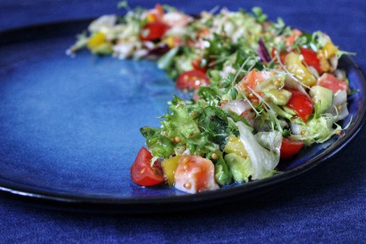 Diet salad of fresh vegetables on a blue plate.Texture or background