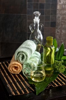 Oil, towels and green leaves on a wooden desk