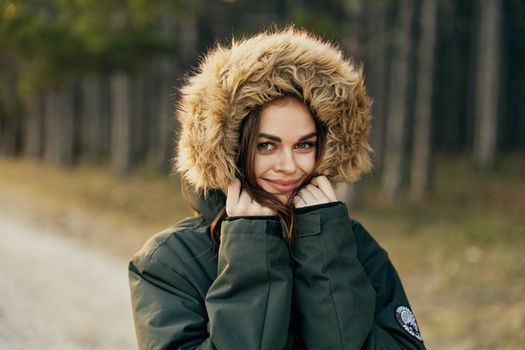 Smiling woman in a jacket with a hood on nature autumn lifestyle. High quality photo