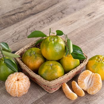 Fresh ripe tangerine mandarin orange in a box wite fresh leaves on wooden table background harvest concept.