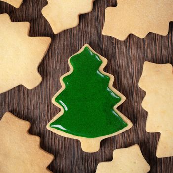 Top view of decorated Christmas tree gingerbread cookie on wooden table background with copy space, concept of holiday celebration.