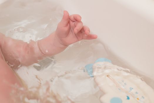 Cute baby having bath in white tub.