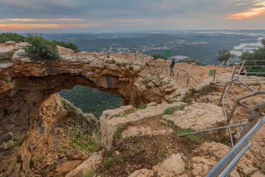 Adamit, Israel - November 24, 2020: Sunset view of the Keshet Cave, a limestone archway spanning the remains of a shallow cave, with visitors, in Adamit Park, Western Galilee, Northern Israel