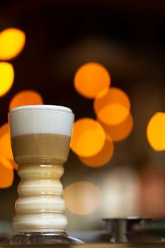 Glass cup with latte on a background of blurry bokeh lights.