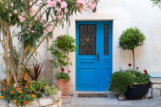 Beutiful vintage courtyard with lush greenery and marine blue wooden door in old Mediterranean costal town, Croatia.