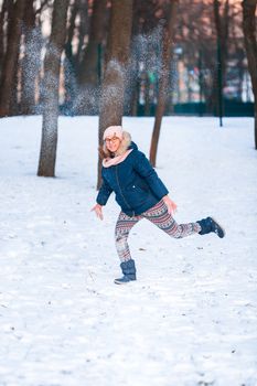 Happy teenage girl having a snowball fight, ready to throw a snowball, playing snowballs in winter park