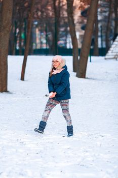 Happy teenage girl having a snowball fight, ready to throw a snowball, playing snowballs in winter park