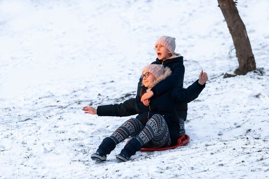 Little girls sliding from the hill in winter park