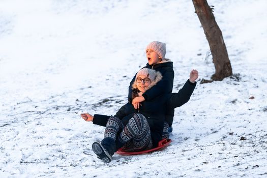 Little girls sliding from the hill in winter park