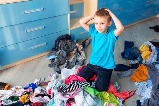 Small boy desperate with the mess in his clothes in his bedroom.