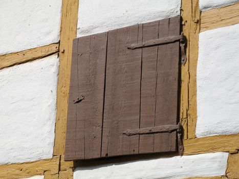 A wooden hatch is situated on the side of a half-timbered house.