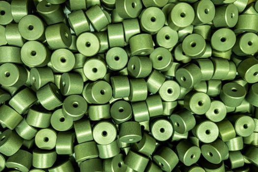 full frame batch of aluminium cylinder parts after anodizing with filling in green chromate solutions, flat industrial background