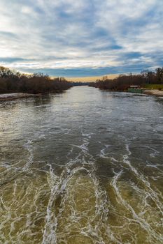 Cloudy landscape over Odra river near water dam with trees around