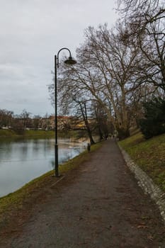 Long pathway in park with trees and high black lanterns around