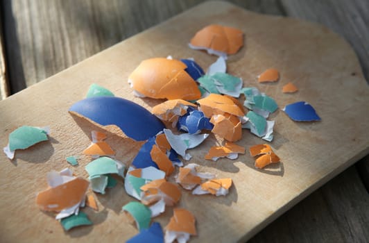 Colorful broken Easter eggshells on a wooden cutting board