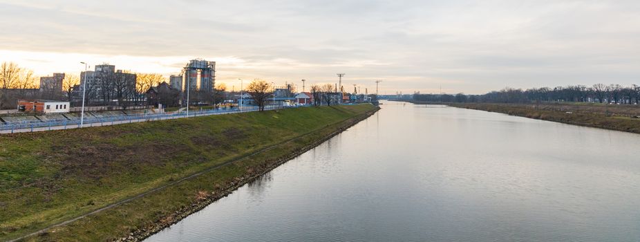 Panorama of Long green coast near Odra river with few trees and buildings
