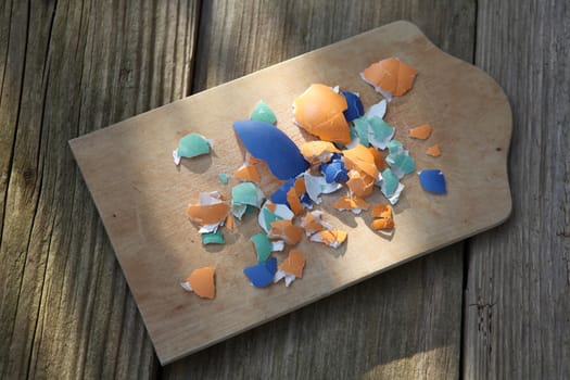 Colorful broken Easter eggshells on a wooden cutting board