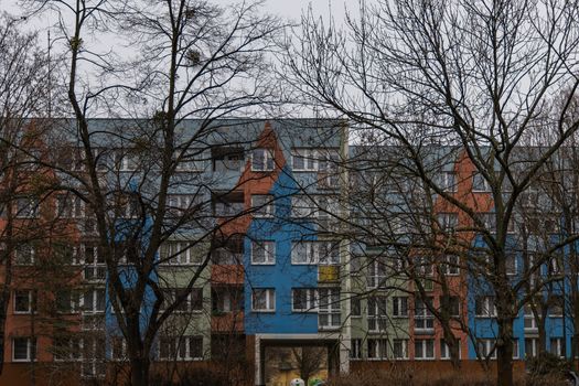 Facade of colorful block of flats behind winter trees