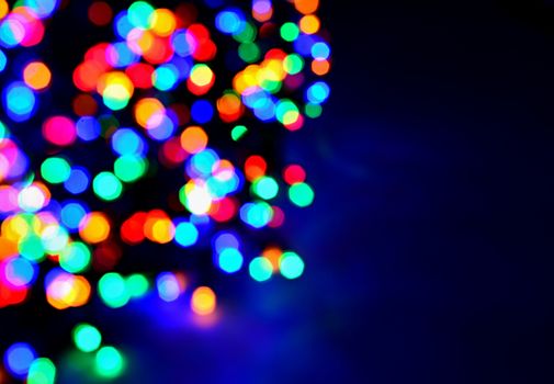 Blurred glittering christmas LED multi color lights, circle color bokeh on dark background.